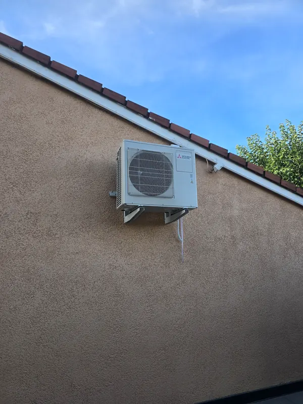 Groupe extérieur Mitsubishi Electric posé sur équerres murales, sous le débord de toit