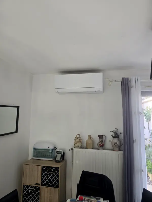 Climatiseur mural Mitsubishi Electric installé au-dessus d'un radiateur, dans une salle à manger